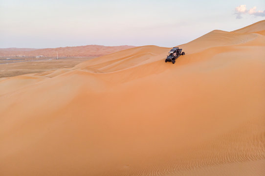 aeril view of Liwa desert, dune buggy driving down a dune © katiekk2