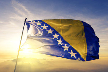 Bosnia and Herzegovina flag textile cloth fabric waving on the top sunrise mist fog