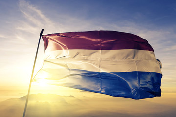 Netherlands Holland Dutch flag textile cloth fabric waving on the top sunrise mist fog