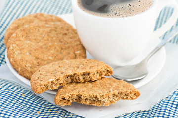Homemade shortbread cookies made of oatmeal are stacked with hot coffee cup on cloth and paper on white table background. Concept food healthy snack for enjoy in holiday.