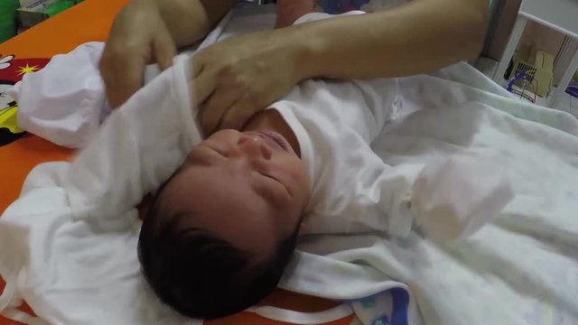 nurse undresses infant boy during pediatric medical checkup