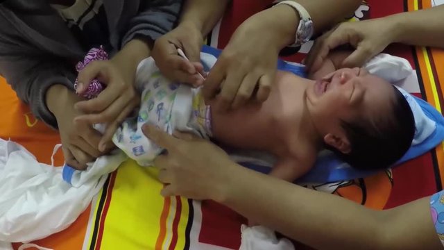 nurse daubing cotton with alcohol to infant and placing plaster