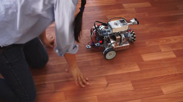 Learning process in robotics school. Curious kid playing with self made robot managed from the constructor, child learns robot constructing.