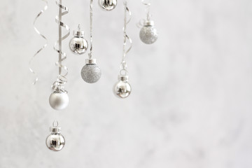 Fototapeta na wymiar Trendy christmas background. Silver ball Ornaments hanging on gray stone background. minimal christmas concept.