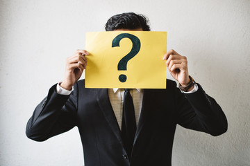 Young adult asian businessman holding yellow signboard paper with QUESTION MARK. Concept of...