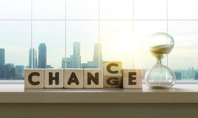 Wooden blocks with the word Change-Chance and sand clock on table with panoramic city skyline...