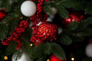 Red Christmas ball on a Christmas tree with a garland on the background