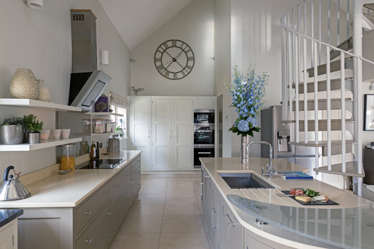 Modern kitchen area with spiral staircase leading to next level.