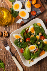 Delicious salad of fresh spinach, boiled egg, tomatoes, nuts and sunflower seeds