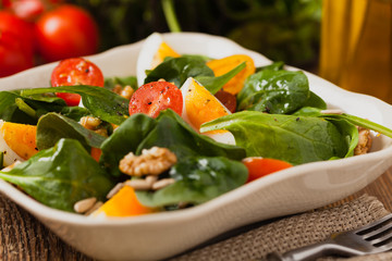 Delicious salad of fresh spinach, boiled egg, tomatoes, nuts and sunflower seeds