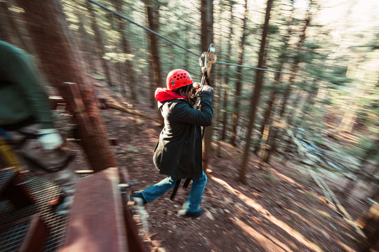 A young man zips through the woods on an outdoor zip line course