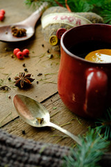 Details of still life in the living room home interior. Beautiful cup of tea with spices and sweaters on a wooden background. Cozy autumn-winter concept.