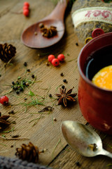 Details of still life in the living room home interior. Beautiful cup of tea with spices and sweaters on a wooden background. Cozy autumn-winter concept.