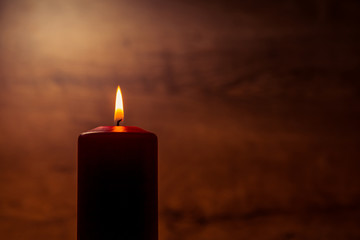 A burning candle on a dark orange background
