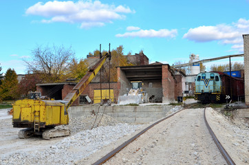 View of the industrial site of the plant for processing gypsum stone. Construction and special equipment, train with cars, excavator and bulldozer