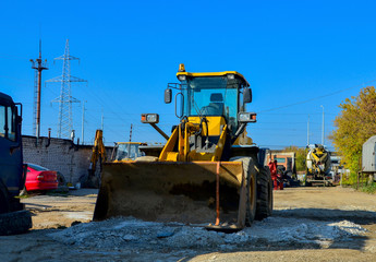 Yellow excavator on the construction site is preparing to load the soil into the dump truck. Wheel loader with iron bucket