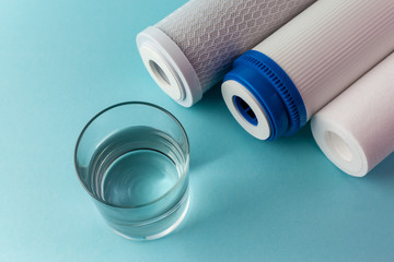 A glass of water on the background of filter cartridges top view