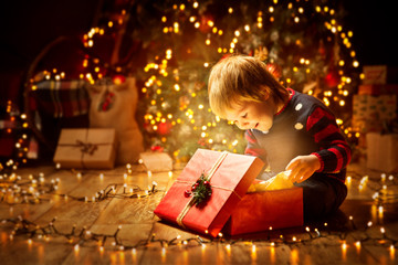Christmas Child Open Present Gift, Happy Baby Boy looking to Magic Light in Box, Kid sitting front...