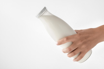 Female hand holding a bottle with natural milk on a white background.