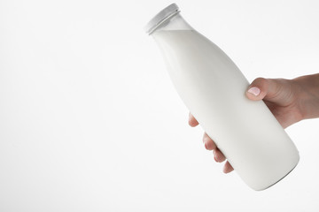 Female hand holding a bottle with natural milk on a white background.
