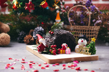 Christmas chocolate roll cake placing together with snowman, Santa Claus sugar, Christmas tree and blue burry. Celebration concept for Merry Christmas day and New year