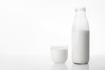  Photo of a bottle of milk and a glass on a white background.