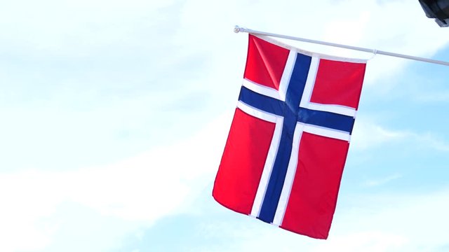 Norwegian flag waving on wind in slow motion against blue sky. National landmark