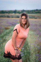 Girl in a short dress in peach color, stands leaning forward