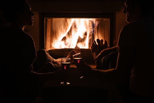 People in dark enjoying wine near fireplace