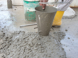 Construction workers doing slump test using specific equipment at the construction site. Witness by consultant. 