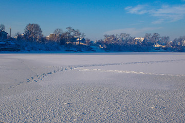 Snow tracks on an empty winter landscape at the outskirts of a village on a cold winter morning. Frozen Mogosoaia Lake, Romania.