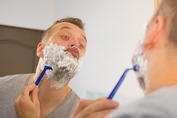 Guy shaving his beard in bathroom