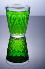 Glass with green drink. Green on black.