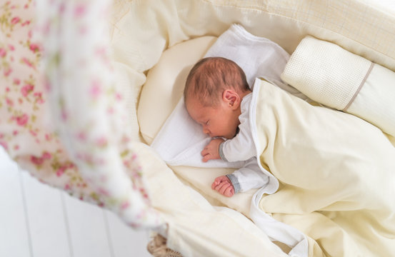 Cute little baby lying in white cradle at sunny day