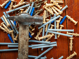 Plastic dowel screws and hammer on wooden background. Selective focus.