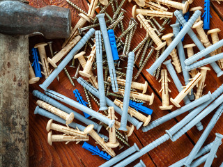 Plastic dowel screws and hammer on wooden background. Selective focus.