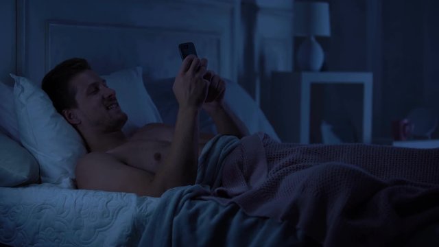 Handsome man flirting on smartphone and smiling, chatting on dating site, gadget
