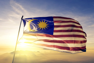 Malaysia Malaysian flag textile cloth fabric waving on the top sunrise mist fog