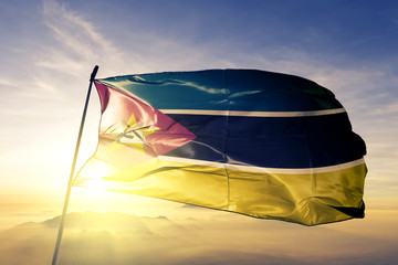 Mozambique Mozambican flag textile cloth fabric waving on the top sunrise mist fog