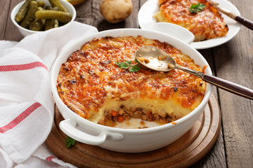 Shepherd's pie, traditional British dish with minced meat and mashed potato on rustic wooden table.