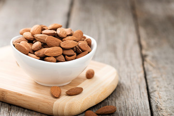 Almonds nuts in wooden bowl on rustic table.