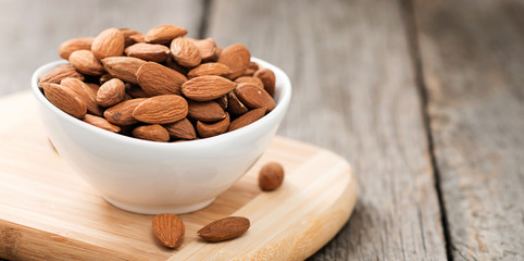 Almonds nuts in wooden bowl on rustic table.
