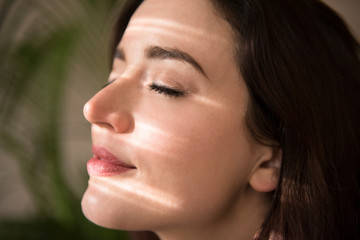 Woman enjoying sunlight coming through window