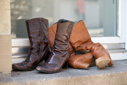 Old boots thrown away on a window sill. Female boots with heels.