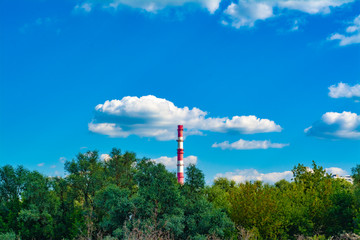 Obraz premium Countryside panorama with forest and blue sky with clouds and factory chimney