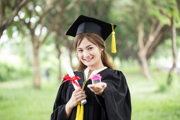 Beautiful Attractive Asian Graduate woman in cap and gown smile holding certificated and House...