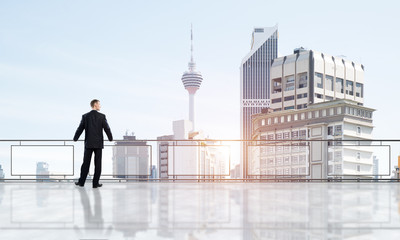 Sunrise above skyscrapers and businessman facing new day