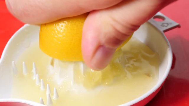 Male hand squeezing fresh lemon fruit using plastic juice squeezer. Making healthy citrus sour drink. Slow motion