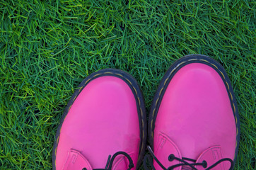Creative pink shoes on green grass. Spring background