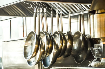 Metal pans hang in the kitchen. Decorative kitchen for cooking courses